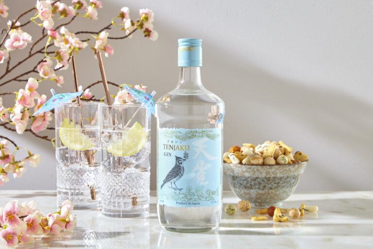 Tenjaku Gin bottle with two garnished glasses, blossoms and Japanese snack mix.